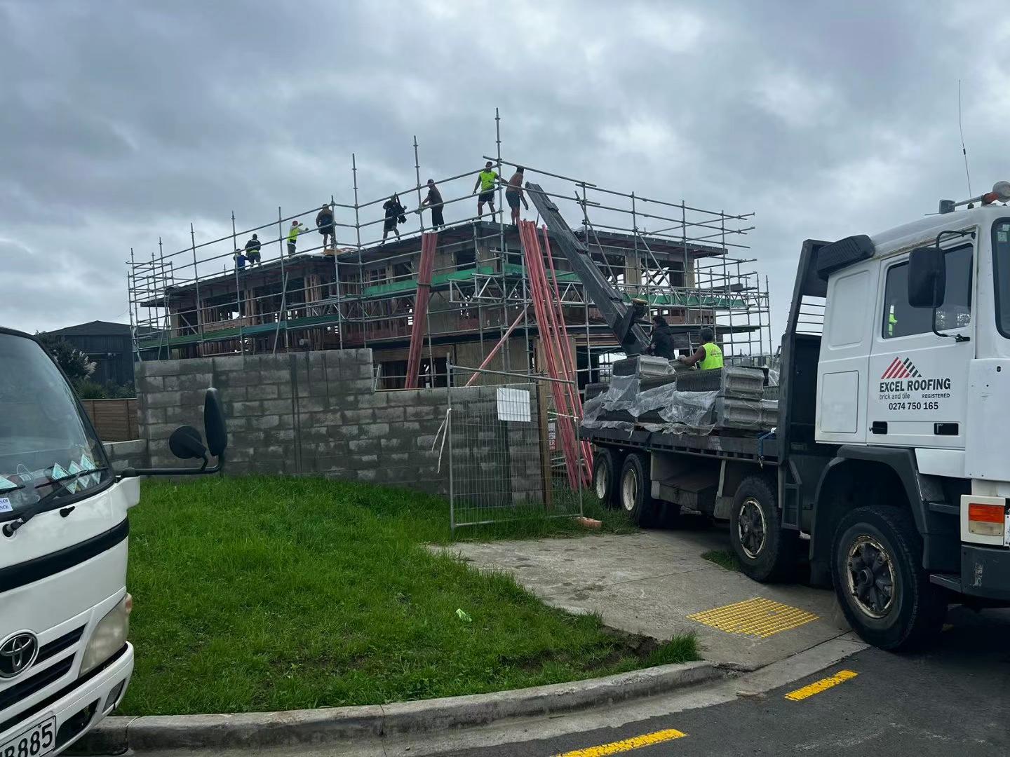 Excel Roofing truck-mounted conveyor loading roof tiles to a building site